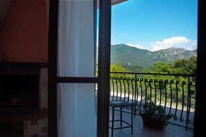 A balcony with a view of mountains, a potted plant, and a metal railing. - Sunsets apartment (Pietre)