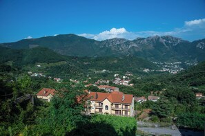 A mountainous landscape with a town and a prominent building with a red roof. - Sunsets apartment (Pietre)