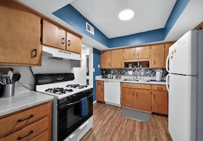 A kitchen with wooden cabinets, a stove, a dishwasher, and a refrigerator.