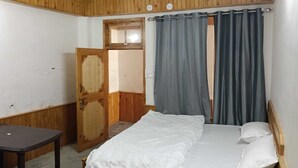 A room with a bed, a table, and a wooden door.