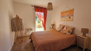 Quarto com cama, um quadro, luminária e janela com cortinas.