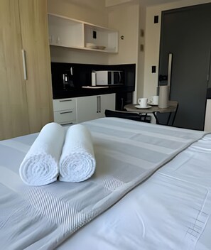 A hotel room with a neatly made bed, a small kitchenette, and a dining area. - Flat Beira mar João Pessoa (João Pessoa)