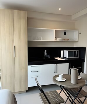 Una cocina moderna con armarios blancos, una encimera negra y un comedor con mesa y sillas.
