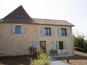 Un bâtiment à deux étages, doté d’un toit en pente, de murs en pierre et de nombreuses fenêtres équipées de volets.