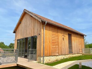 Un bâtiment en bois doté de grandes fenêtres, d’une fondation en pierre et d’une rambarde en métal.