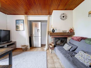 Una sala de estar con televisor, sofá, chimenea y un reloj en la pared.