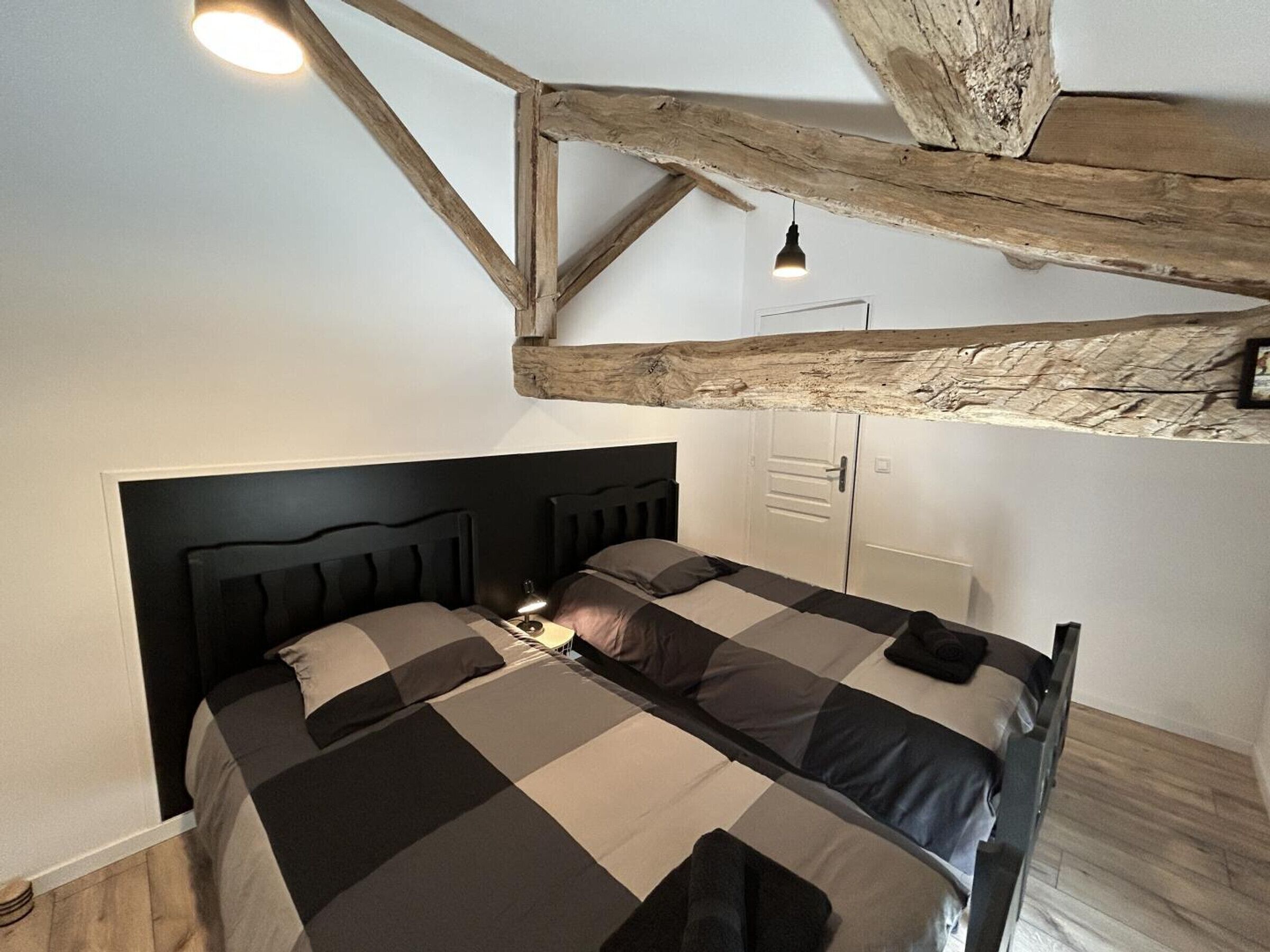A bedroom with a bed, a desk, and a wardrobe.