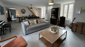 A living room with a grey sofa, a wooden coffee table, a green armchair, a bookshelf, and a guitar. - House with private pool, pets allowed - 6 guests (Courcôme)