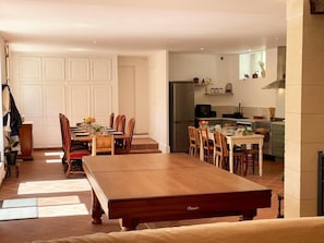 Un coin repas avec une table et des chaises en bois, une cuisine équipée et une porte blanche.