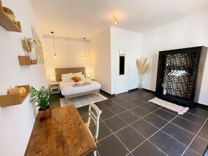 Une chambre moderne avec un lit, des tables de chevet, une table en bois et une plante en pot.