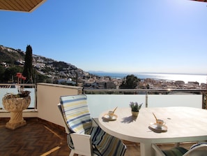 A terrace with a round table, chairs, and potted plants. - Apartment with AC, sea view - 4 guests (Roses)