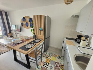Eine moderne Küche mit Essbereich, einem Kühlschrank, einer Spüle und einem Fernseher.