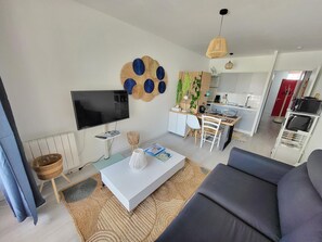 Ein modernes Wohnzimmer mit einem Flachbildfernseher, einem weißen Couchtisch und einem Sofa.