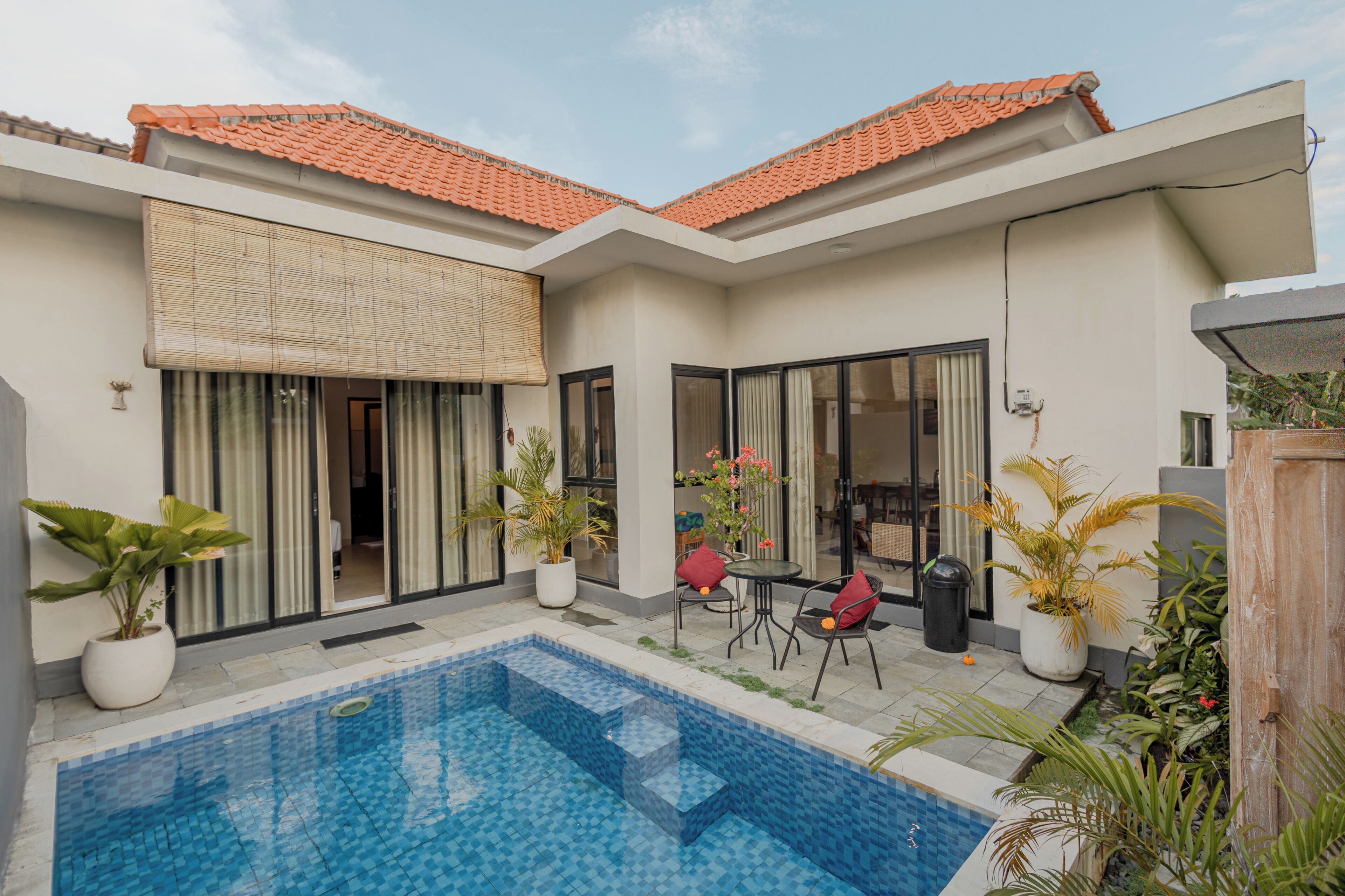 Ein modernes Haus mit Swimmingpool, großen Fenstern und Topfpflanzen.