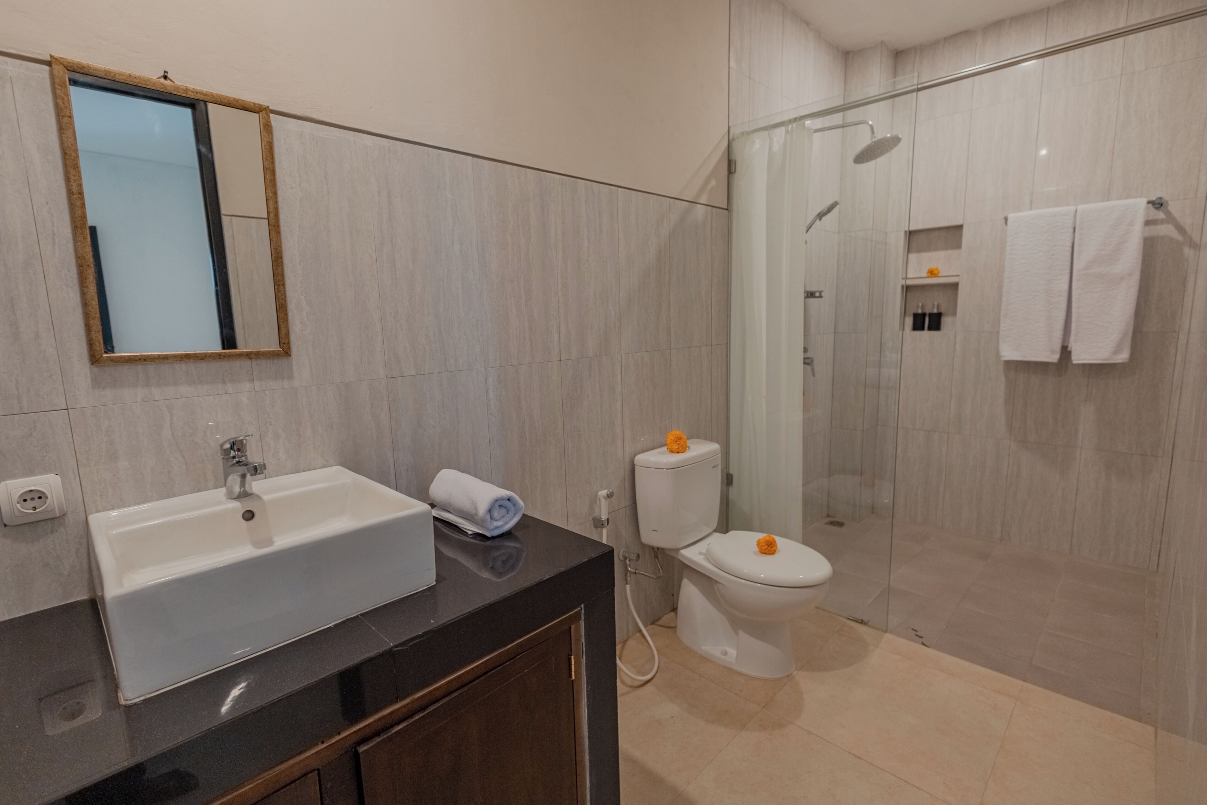 A modern bathroom with a sink, mirror, toilet, and shower area.