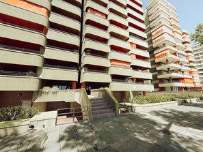 A multi-story building with balconies, a staircase, and a paved area with plants. - Spacious apartment with sea view - 6 guests (Platja d'Aro)