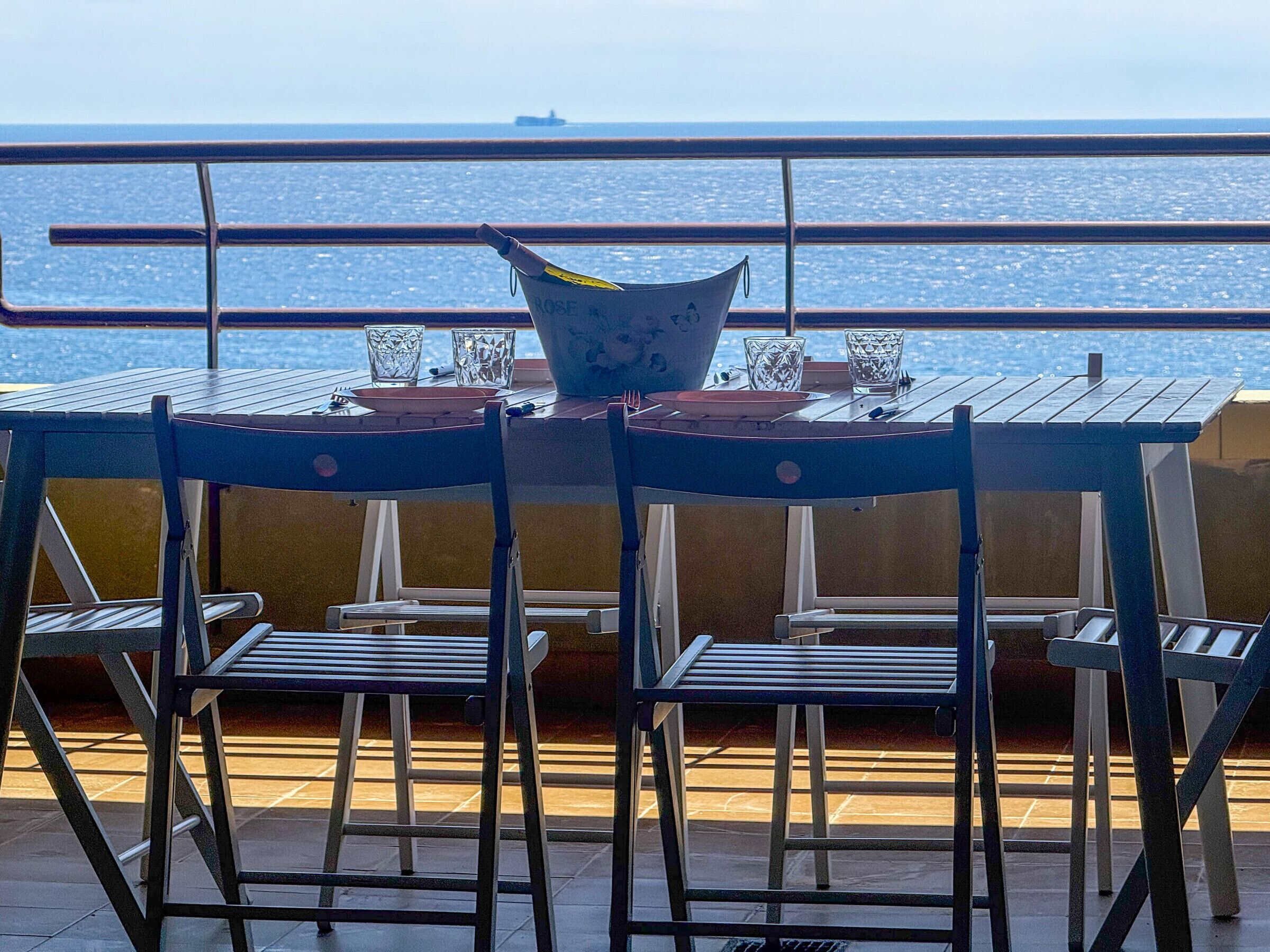 A table with chairs and a decorative bowl, overlooking a body of water.