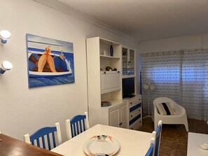 Ein Essbereich mit Tisch, Stühlen, einem Gemälde, einem Fernseher und einem Ventilator.