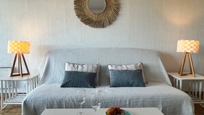 Een slaapkamer met een bed, twee nachtkastjes, een ronde spiegel en een salontafel met decoratieve objecten.