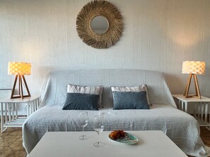 Ein Schlafzimmer mit einem Bett, zwei Nachttischen, einem runden Spiegel und einem Couchtisch mit Dekoration.
