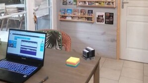 A laptop on a table with a sticky note, a small box, and a bookshelf with books. - Chalet, AC, 6 guests (Noves)
