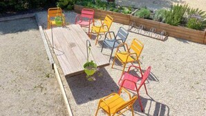 A wooden table with chairs in a garden area. - Chalet, AC, 6 guests (Noves)