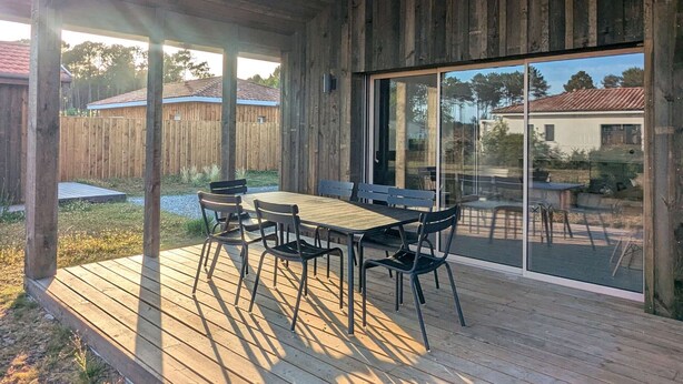 Une terrasse extérieure couverte, dotée d’un sol en bois, d’une table et de chaises.
