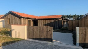 Un bâtiment moderne avec un toit recouvert de tuiles rouges, une clôture en bois et une allée pavée.
