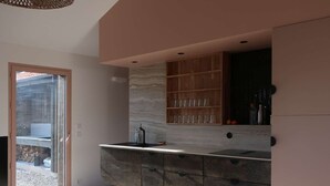 Une cuisine moderne avec un plan de travail en marbre, des armoires en bois et une porte vitrée donnant sur l’extérieur.