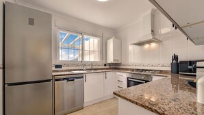 A modern kitchen with stainless steel appliances, white cabinetry, and a granite countertop. - Bungalow Rental in Calpe: BONITA (Calpe / Calp)