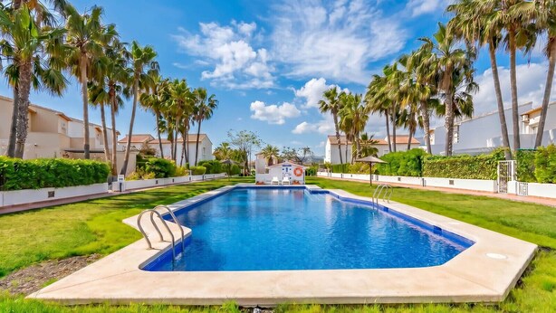 A swimming pool with a lifeguard tower, surrounded by palm trees and a clear sky. - Bungalow Rental in Calpe: BONITA (Calpe / Calp)