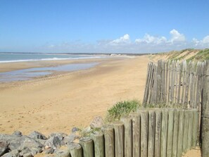 Ein Strand mit einer Holzlattenverkleidung und Felsen im Vordergrund.