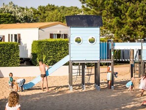 Un espace de jeux sur la plage avec un toboggan et des structures d’escalade.