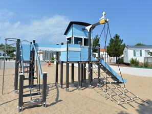 Une aire de jeux avec des structures d’escalade et un toboggan.