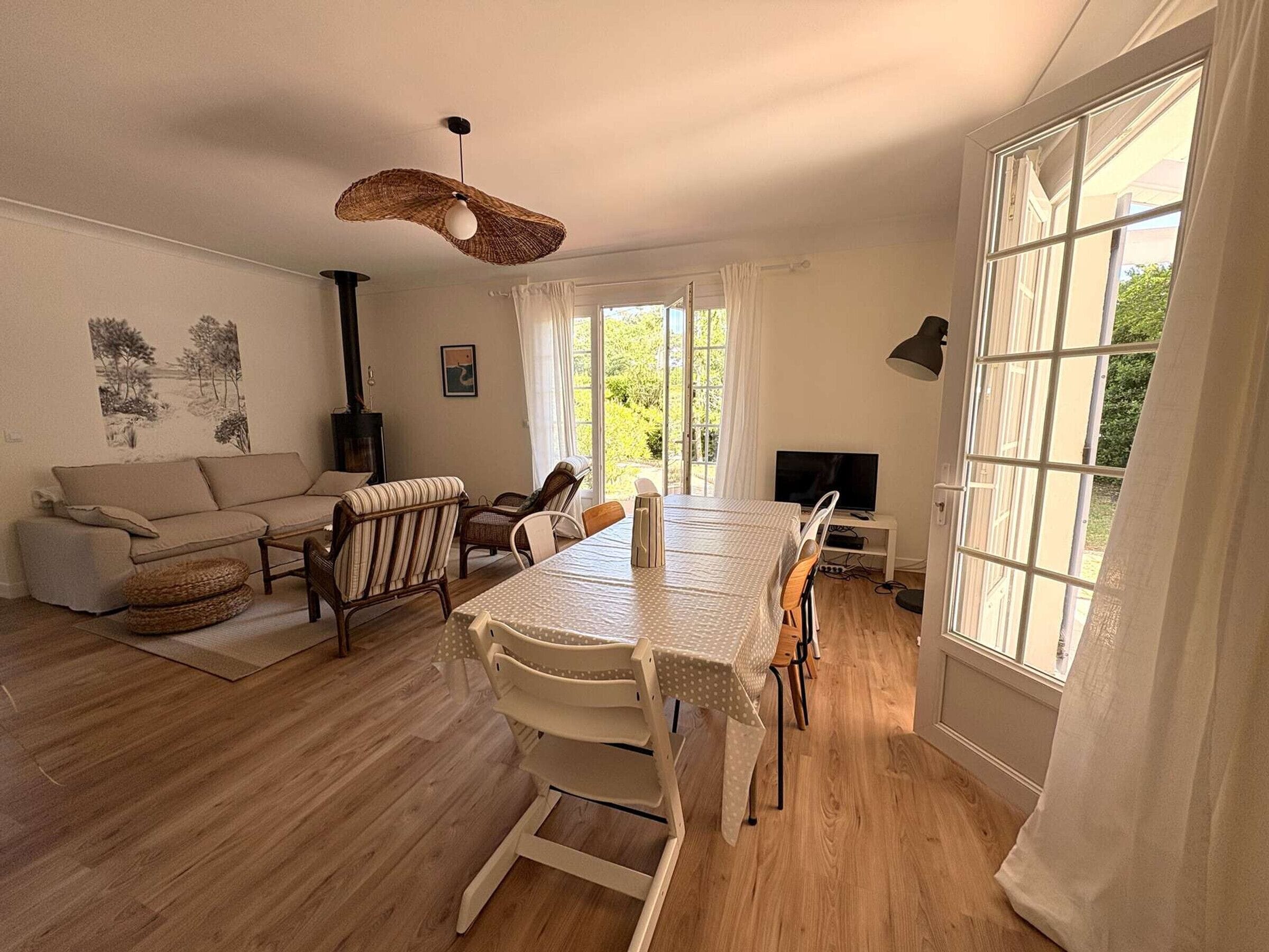 A living room with a sofa, chairs, a dining table, a TV, and a fireplace.