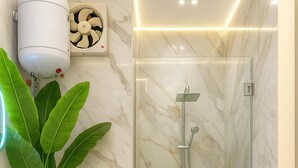 Une salle de bain moderne avec une douche en verre, des toilettes, un lavabo et une plante en pot.