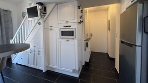 Ett kök med vita skåp, en inbyggd ugn, ett kylskåp och en trappa som leder till ett annat våningsplan.
