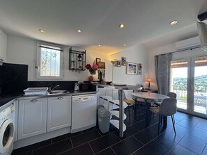 Eine moderne Küche mit integriertem Geschirrspüler, ein Essbereich mit rundem Tisch und Stühlen sowie ein Balkon mit Blick.