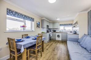 Eine kleine Küche mit Waschmaschine, Esstisch mit Stühlen und einer Couch.