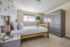 Ein Schlafzimmer mit Bett, Kleiderschrank, Heizkörper, Fenster und Lampe.