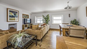 A living room with a sofa, a coffee table with a plant, a TV, and a dining area with a wooden table and chairs. - Spacious Flat with Gorgeous Views - Pass the Keys (Bognor Regis)