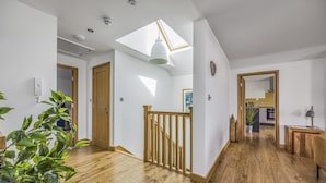 A modern interior with wooden flooring, a skylight, a staircase, and a view into a kitchen. - Spacious Flat with Gorgeous Views - Pass the Keys (Bognor Regis)