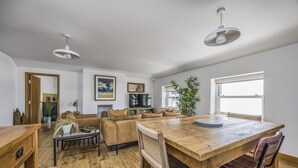 A spacious living room with a wooden dining table, leather sofas, and a fireplace. - Spacious Flat with Gorgeous Views - Pass the Keys (Bognor Regis)