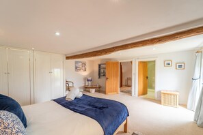 Ein Schlafzimmer mit einem Bett, einer Holztür, einem Sessel, einem kleinen Tisch und einem Bild an der Wand.
