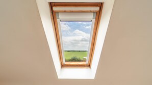 Ventana de tragaluz con vista a un campo verde y un cielo nublado.