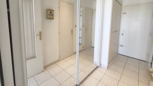 A hallway with white doors, a mirror, and a tiled floor. - Studio with AC and terrace - 2 guests (Cap d'Agde)