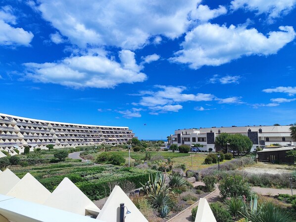 Ein moderner Gebäudekomplex mit mehreren Wohneinheiten, einem angelegten Gartenbereich und blauem Himmel mit Wolken.