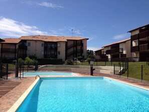 Ein Poolbereich mit blauem Himmel, umgeben von mehrstöckigen Gebäuden mit Balkonen.