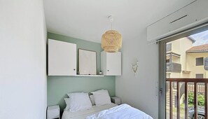 Ein Schlafzimmer mit einem Bett, zwei Nachttischen, einer Hängelampe, einem Wandspiegel und einem Traumfänger.