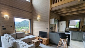 Un interior moderno con un sofá, televisor, armarios de madera y una zona de comedor.